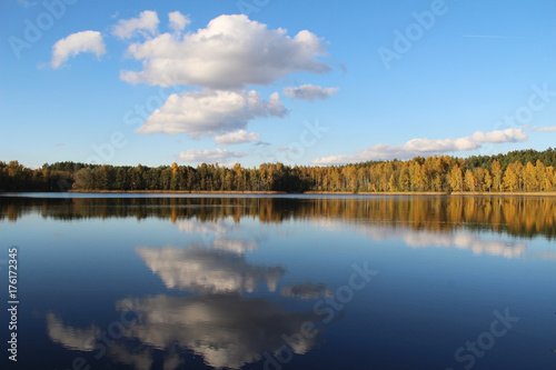 Lake in a delightful autumn forest at sunny day. Autumn trees with reflection. Russia.