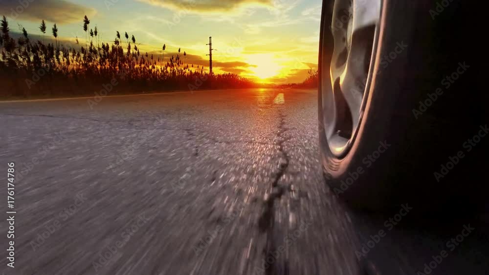 Drive on asphalt at sunset against bright setting sun with 