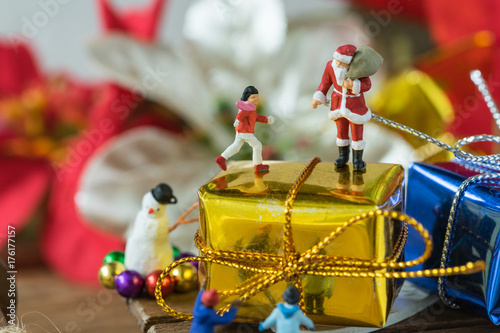 miniature figure Santa claus standing on big golden present gift box on sleigh with happy children as christmas celebration concept