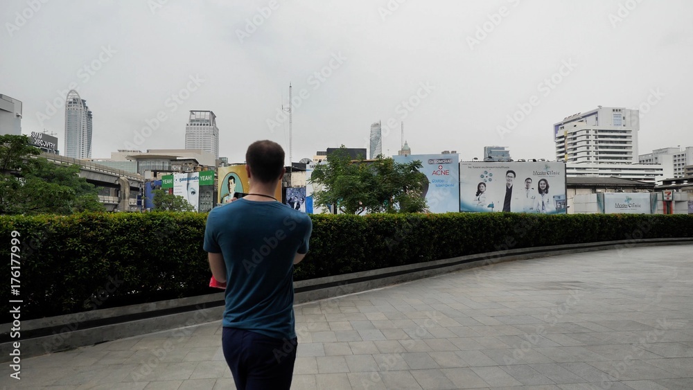 Man walks down the street and photographs on the smartphone. Man making photo with his mobile on the street. Young man photographing on the street
