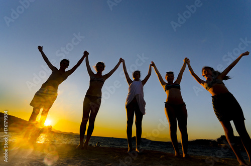 silhouette friends hands up. sunset water