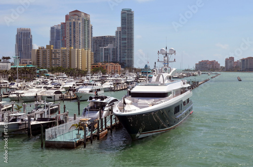 Mega luxurious motor yacht docked at a marina in Miami Beach with luxury high-rise condominiums over looking the marina and the Atlantic Ocean in the background. © Wimbledon