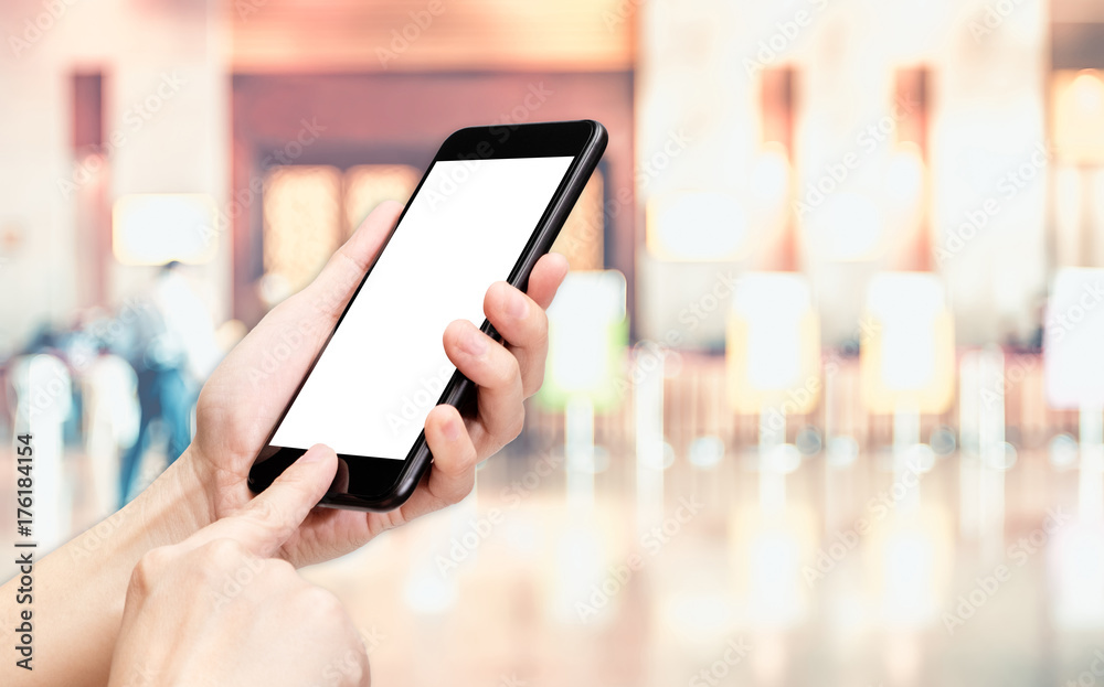 Hand click mobile phone with blur office corridor hall way background bokeh light,White screen mock up template for adding your design or your text.
