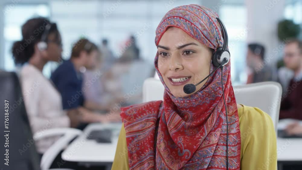 Friendly call center worker wearing hijab talking to a customer on the phone
