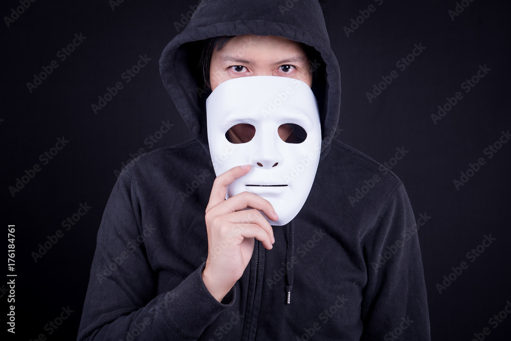 Foto de Mystery man holding white mask for hide his face. Anonymous social  masking or halloween concept. do Stock | Adobe Stock