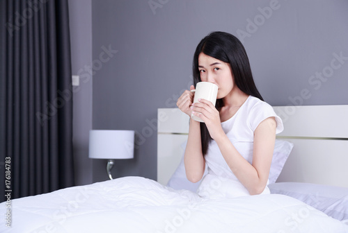 woman on bed with a cup of coffee in bedroom