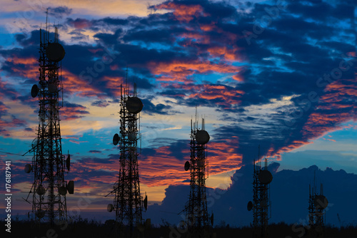 Fotografie Silhouette of the Antenna of cellular cell phone and communication system tower arranged as a bar chart on cloud and blue sky background, Telecommunication technology concept