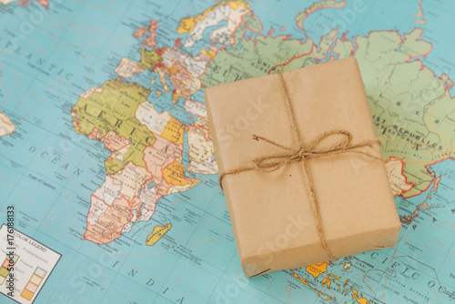 International shipping. Cardboard box on the geographical map background