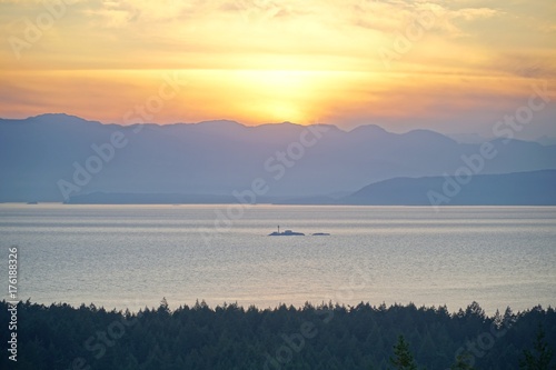 Aussicht vom Wald auf das Meer mit Sonnenuntergang und Wald.