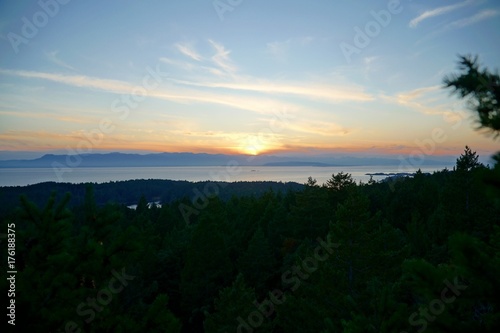 Aussicht vom Wald auf das Meer mit Sonnenuntergang und Wald.
