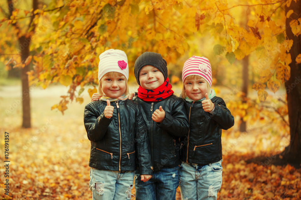 Three happy friends kids hugging and laughing in autumn park Three happy friends kids hugging and laughing in autumn park