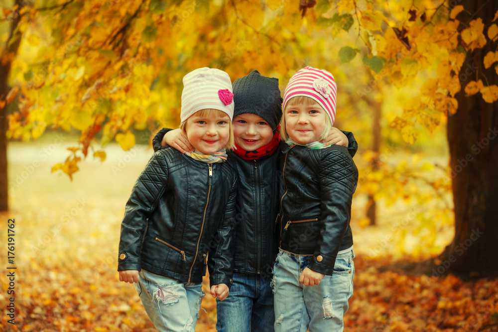 Three happy friends kids hugging and laughing in autumn park Three happy friends kids hugging and laughing in autumn park