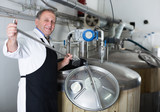Portrait of brewer who is making beer on his workplace