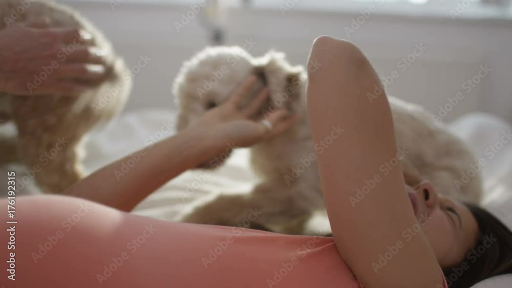 Happy couple relaxing in the bedroom with 2 cute playful young puppies Happy couple relaxing in the bedroom with 2 cute playful young puppies