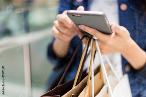 Close up of woman using cellphone and holding shopping bags photo