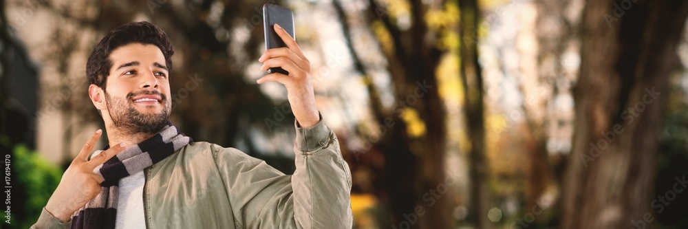 Fototapeta premium Composite image of smiling man taking selfie through mobile