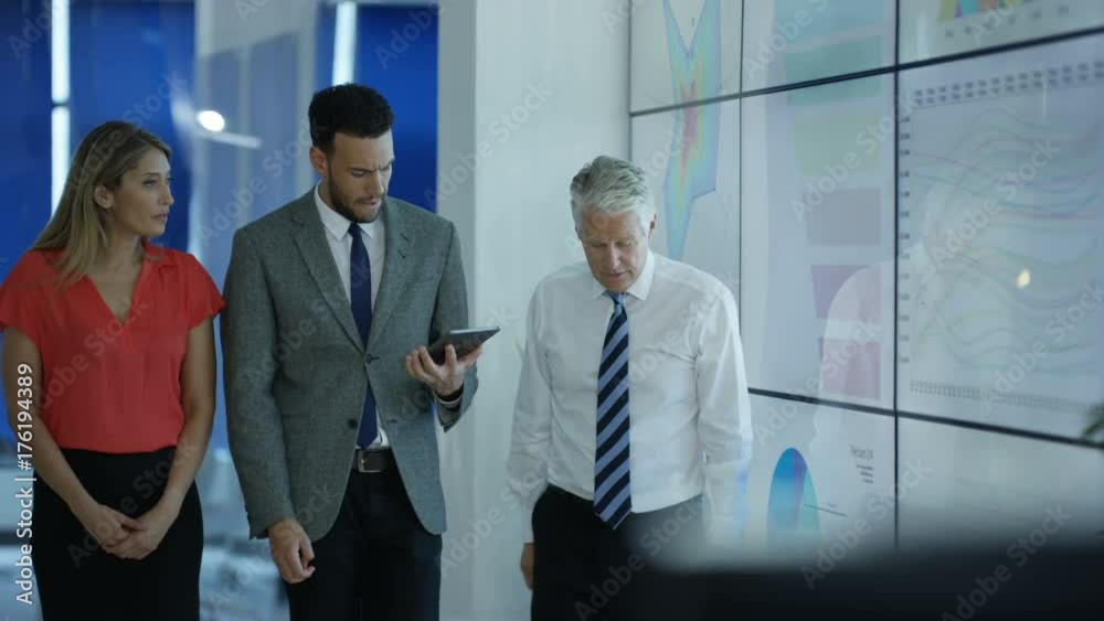Business group in discussion, looking at video wall with charts & graphs Business group in discussion, looking at video wall with charts & graphs