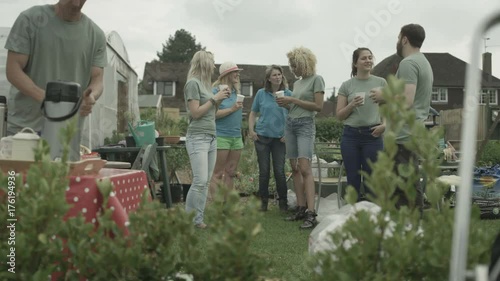  Cheerful group relaxing & chatting with drinks in shared community garden photo