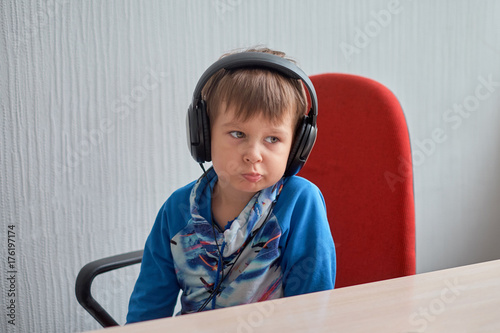 leisure, education, children, technology and people concept - boy with computer and headphones at office photo