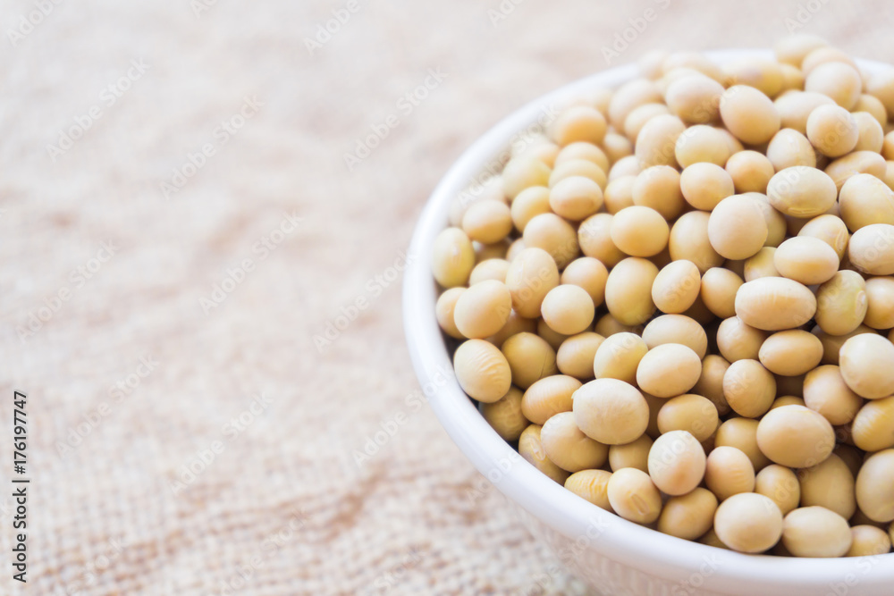 Closeup soy beans on white bowl with sackcloth background , healthy food concept Closeup soy beans on white bowl with sackcloth background , healthy food concept