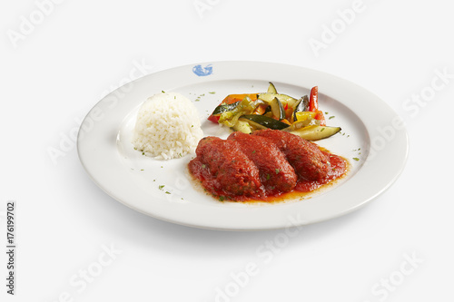 soutzoukakia meatballs greek style with tomate sauce and grilled courgette, onions and papper on white background