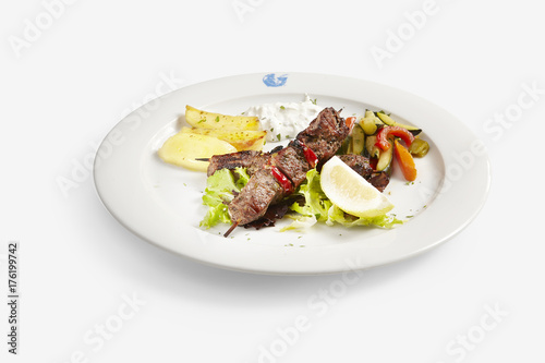 Beef skewer greek style with potatoes and pepper side on white balackground