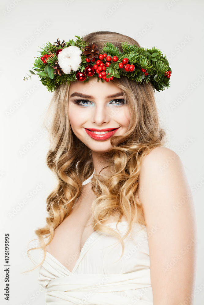 Naklejka premium Beautiful Christmas Woman Fashion Model Woman with Wavy Hairstyle, Makeup and Christmas Wreath with Red Glass Balls, Xmas Tree Twig and Berry