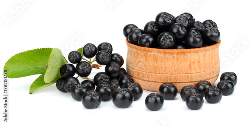 Chokeberry with leaf in wooden bowl isolated on white background. Black aronia