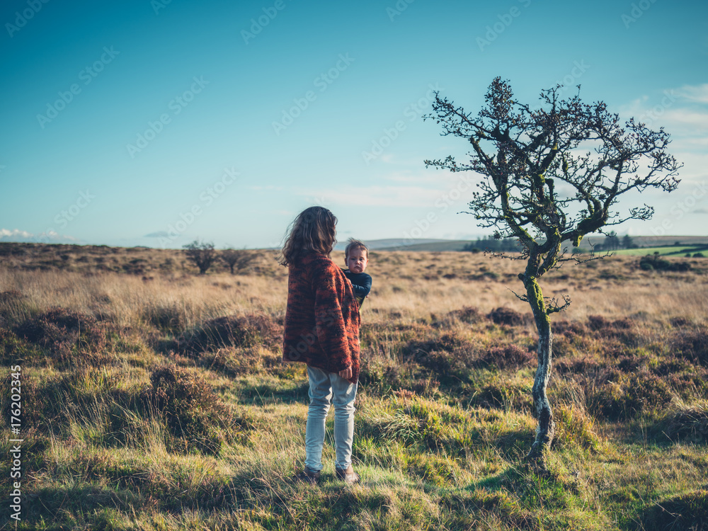 Mother with baby standing by tree in wilderness