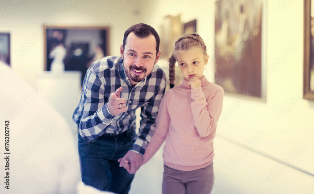 Fototapeta premium satisfied father and daughter regarding paintings in museum