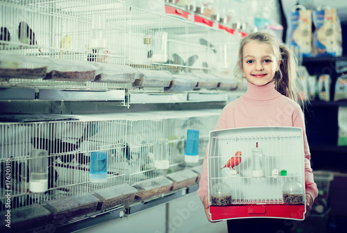 girl customer happy about buying cage with canary bird in pet shop