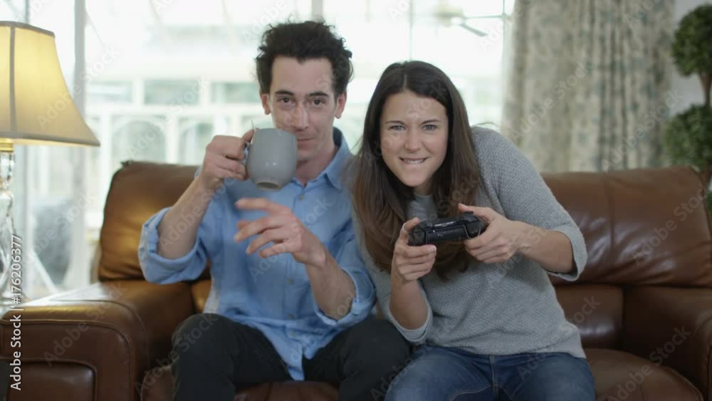 Competitive woman playing video games at home, with boyfriend beside her. Competitive woman playing video games at home, with boyfriend beside her.