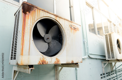 Old air compressor with rust on the wall outdoor