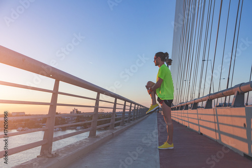 Man stretching after jogging / exercise on a bridge.