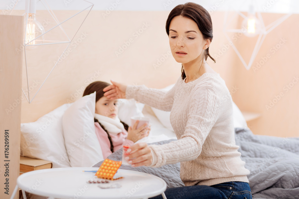 Worried mother putting a pillbox on the table Worried mother putting a pillbox on the table