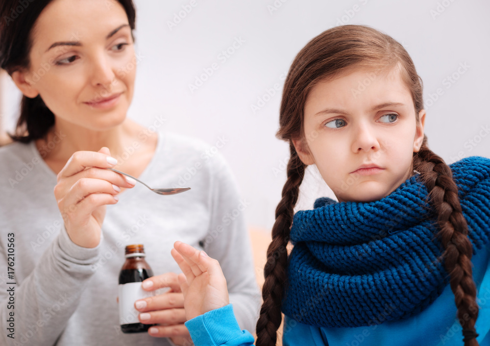 Sad girl turning her face from a mother with helpful medicine Sad girl turning her face from a mother with helpful medicine