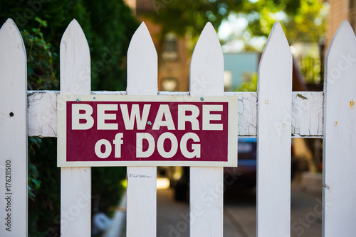 Canvas Print Beware of dog sign on white picket fence