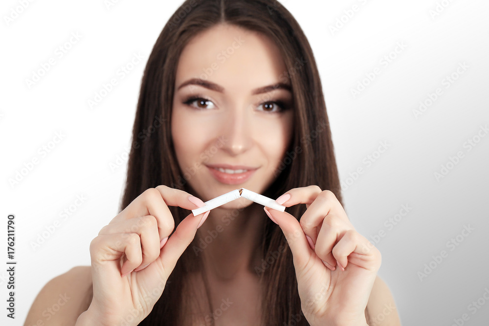 Stop smoking concept. Young woman cut cigarettes with scissors happy smiling. focus on hand, scissors and cigarettes Stop smoking concept. Young woman cut cigarettes with scissors happy smiling. focus on hand, scissors and cigarettes
