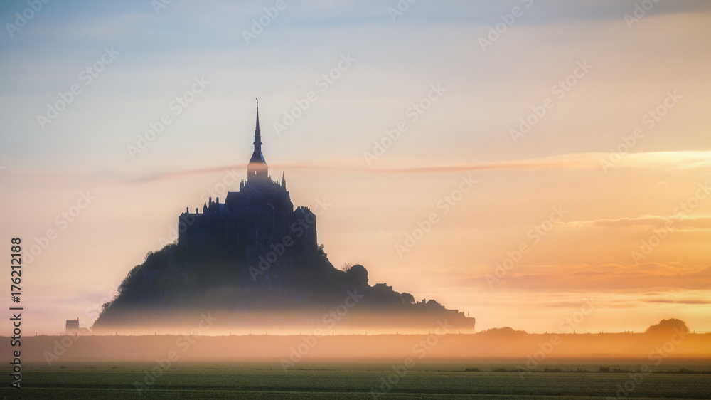 Panoramic view of famous Le Mont Saint-Michel tidal island in beautiful sunrise foggy light, Normandy, northern France
