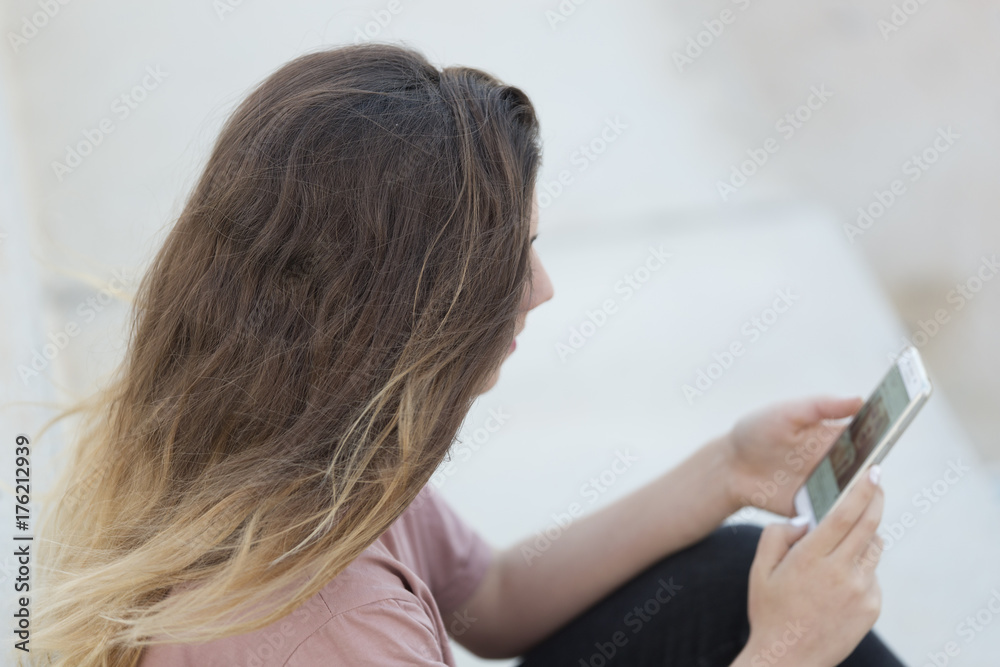 Teenage girl sitting on a ladder with her mobile looking. Teenage girl sitting on a ladder with her mobile looking.
