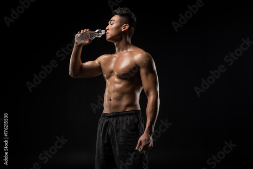 shirtless sportsman drinking water