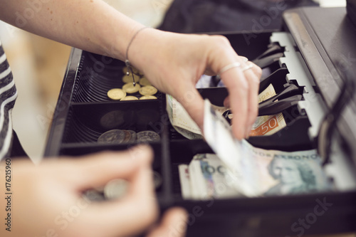 Woman taking money from cash register photo