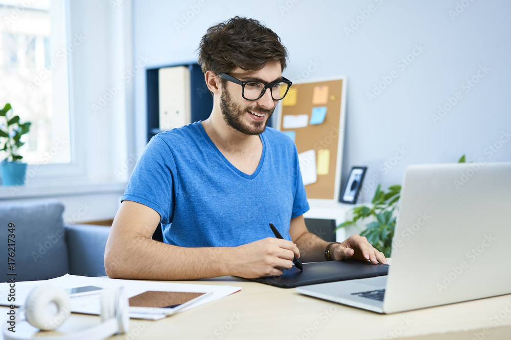 Cheerful graphic designer in home office working on laptop