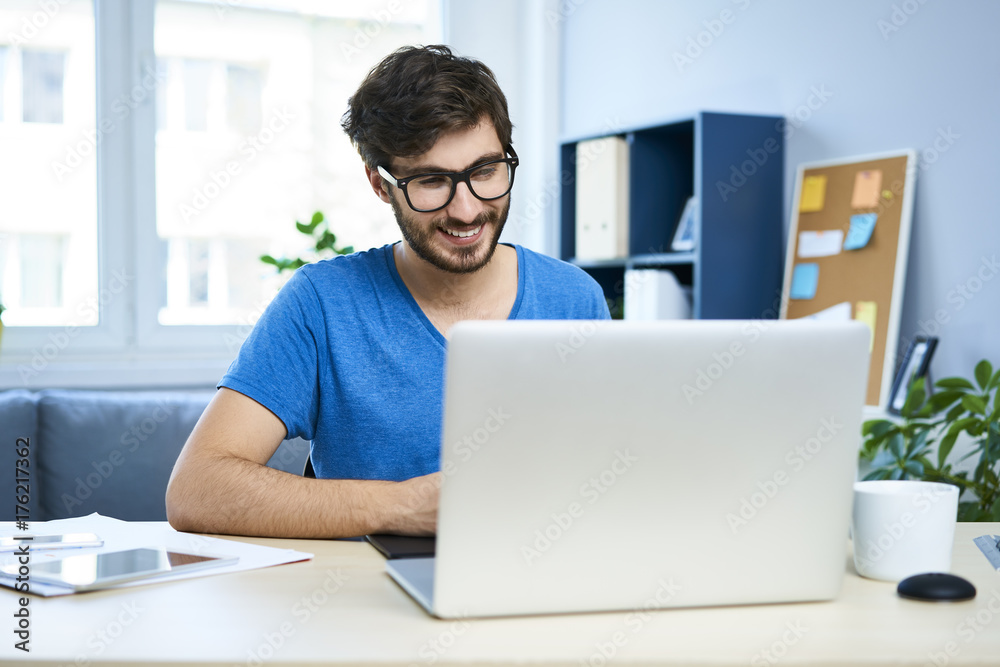 Portrait of young graphic designer working on laptop in home office Portrait of young graphic designer working on laptop in home office