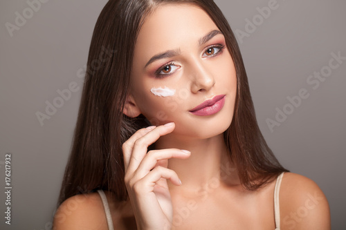 Woman Beauty Face Skin Care. Portrait Of Healthy Young Female Model With Soft Fresh Skin And Stripes Of Facial Cream On Cheeks. Closeup Beautiful Sexy Girl Applying Cosmetics On Skin. High Resolution