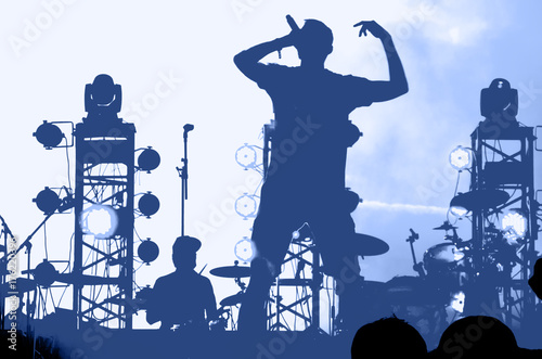 Silhouette of a musician with a microphone on stage. blue toning