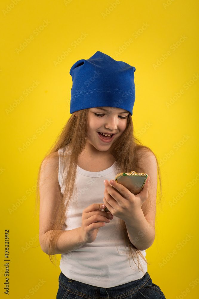 Beautiful caucasian girl posing on yellow isolated background in studio holding in hands mobile phone Beautiful caucasian girl posing on yellow isolated background in studio holding in hands mobile phone