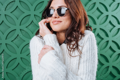  Woman in sweater and sunglasses talking by smartphone © LIGHTFIELD STUDIOS