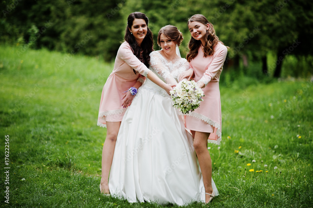 Attractive bride posing and having fun with two her bridesmaids in the park on a sunny spring wedding day.