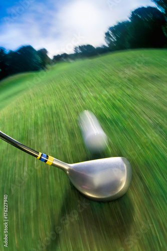 Golf club hitting ball on golf course